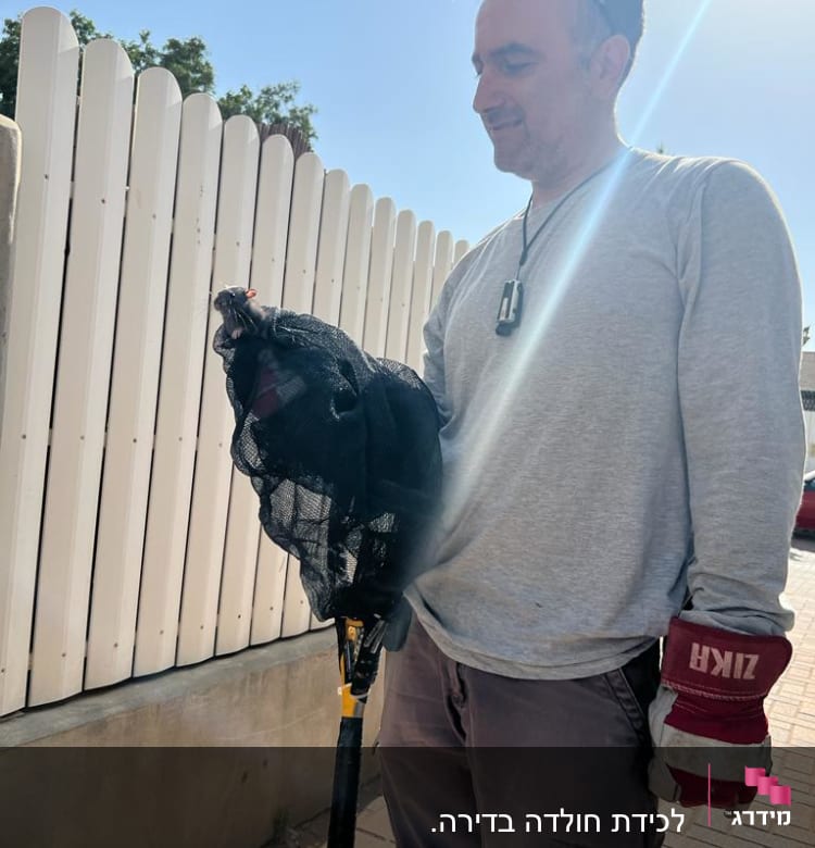 אדם מחזיק רשת לכידת מזיקים בידו